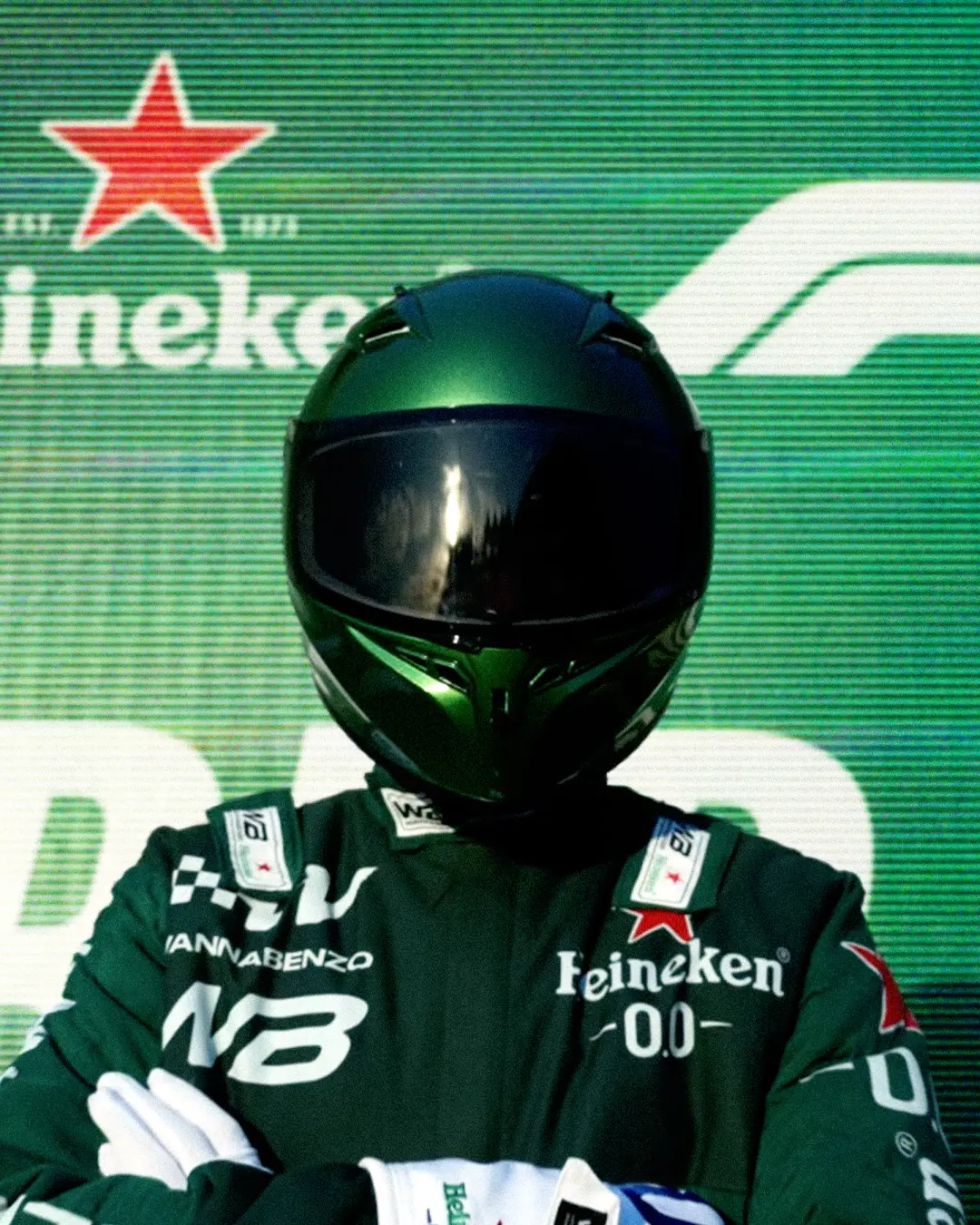 A driver in a green racing suit and helmet at the Heineken Formula 1 experience